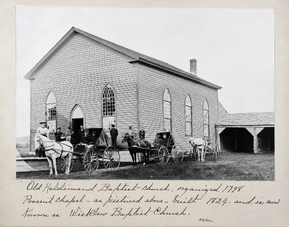 Historic photograph of the white clapboard Wicklow Baptist Church in Ontario, with horse-drawn buggies outside and a handwritten note beneath