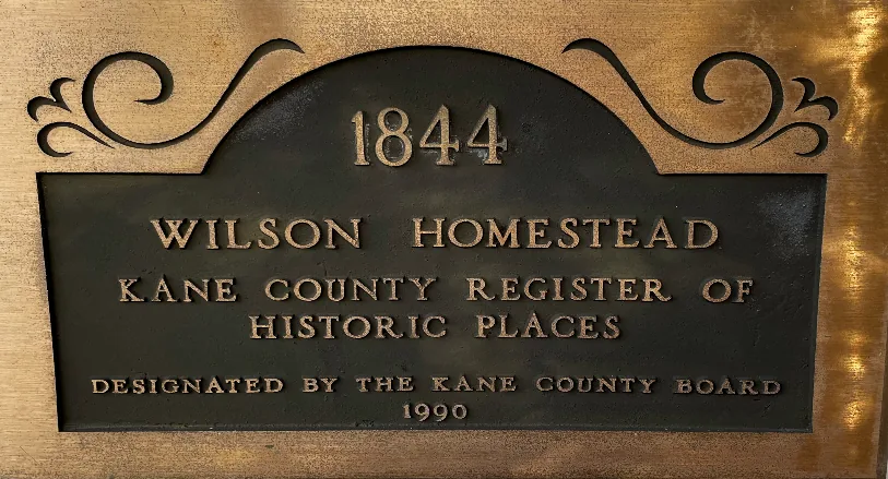 Bronze plaque reading 1844 Wilson Homestead, Kane County Register of Historic Places, designated by the Kane County Board 1990