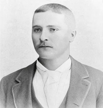 Black-and-white portrait of Martin Jepson as a young man with short hair and a moustache, wearing a jacket and white shirt