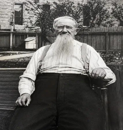 Black-and-white photograph of Wilhelm Gerber in old age, with a long white beard and suspenders, seated outdoors